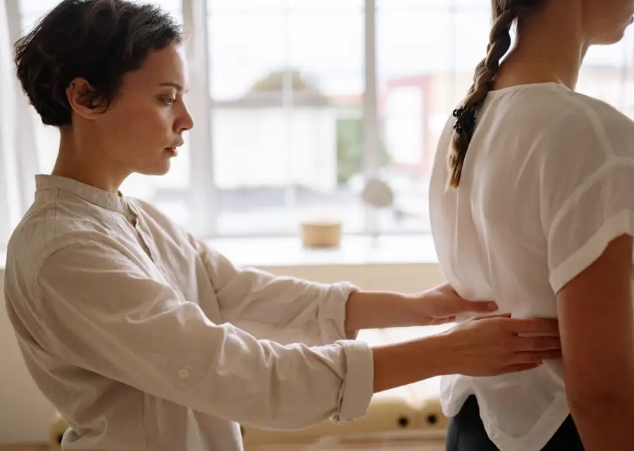 Kinesióloga evaluando la espalda de una paciente