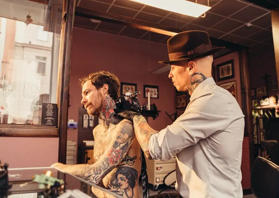 Tatuador trabajando sobre el brazo de un cliente en su estudio